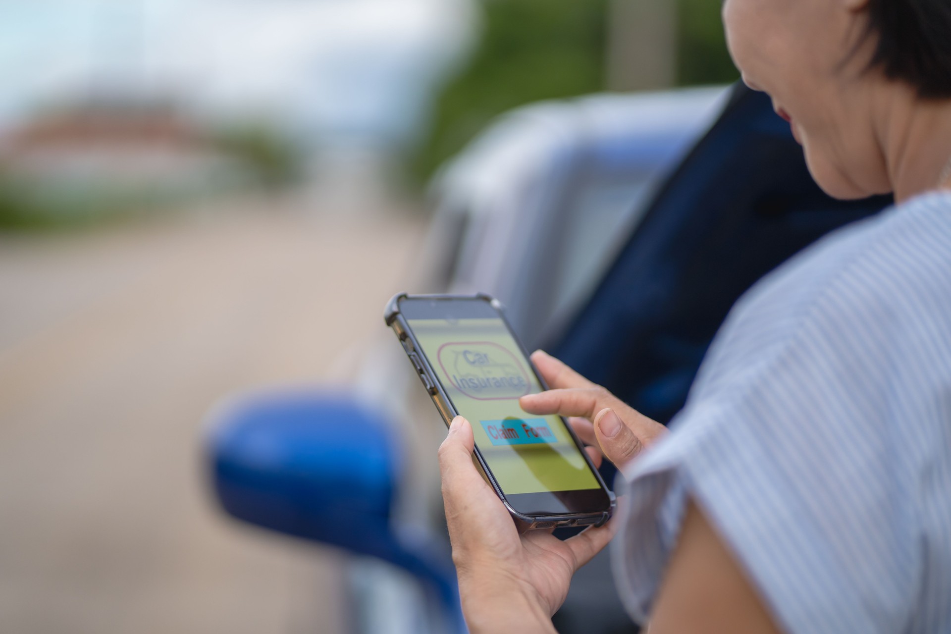 Asian woman fills out insurance claim form via mobile phone app