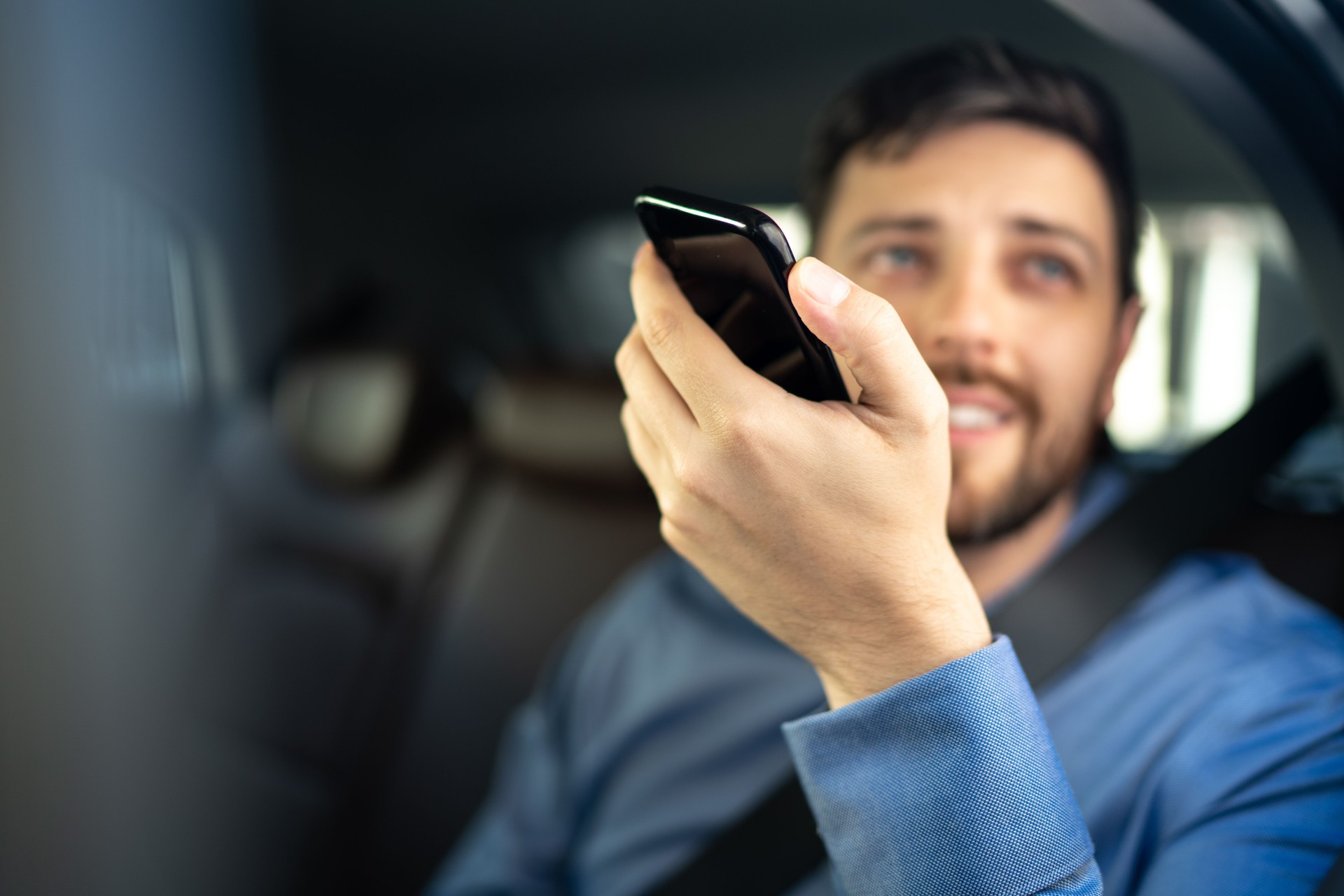 Businessman talking on mobile phone at passenger seat inside a car